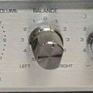 May include: Close-up of a silver stereo receiver with multiple knobs and dials. The knobs are labeled "POWER", "LEFT", "HEADPHONE", "FM", "BALANCE", "TAPE 1", "TAPE 2", "SELECTOR", "PHONO", "AUTO", "MANUAL", "AM", and "TUNING".