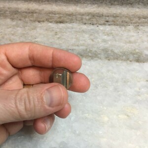 Peut inclure: Un bouton en métal argenté avec un motif de croix.