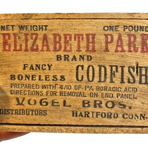 May include: A vintage wooden box for Elizabeth Park brand boneless codfish. The box features red and black text, including "Net Weight One Pound" and "Vogel Bros. Distributors Hartford Conn."