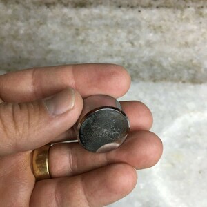 Peut inclure: Un bouton en métal argenté avec une surface légèrement usée.