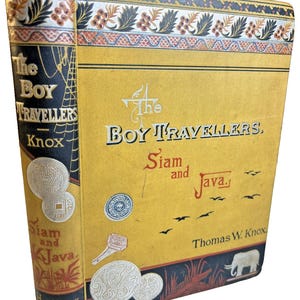 May include: A hardcover book titled The Boy Travellers: Siam and Java by Thomas W. Knox. The yellow cover features illustrations of coins, a seal, and an elephant, with black and red decorative borders. The black spine displays the title and author.