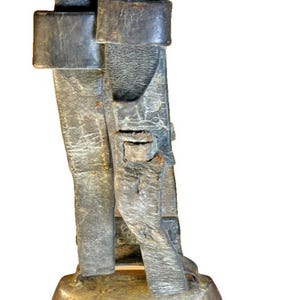 May include: A vintage bronze cowbell with leather straps and buckles. The bell has a rounded base and a weathered appearance. A blue and white can is next to the bell for size comparison.