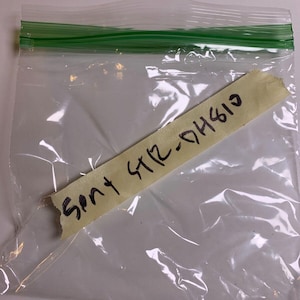 Puede incluir: Una bolsa de plástico transparente con una nota adhesiva amarilla que dice "Sent STR-04613"