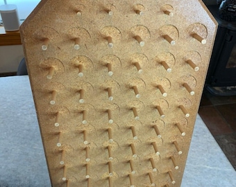 May include: A wooden peg board game with a light brown finish and rows of wooden pegs. The board is in the shape of a house.
