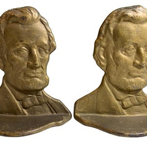 Könnte beinhalten: Paar antike, bronzefarbene Buchstützen, jeweils mit einer Büste von Abraham Lincoln. Die Buchstützen haben ein detailliertes, gealtertes Aussehen mit sichtbarer Textur und Patina. Die Büsten zeigen Lincoln in einem Anzug mit Fliege.
