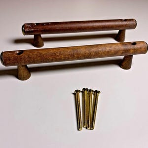 May include: Two wooden cabinet pulls with a dark brown finish and brass accents. The pulls are approximately 6 inches long and come with five gold screws.