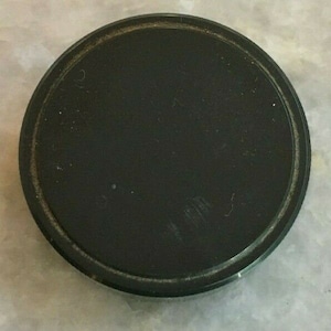 May include: A black, round, plastic lid with a slightly raised edge.