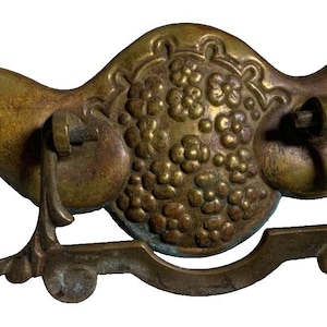 May include: Antique brass cabinet pull with a floral design. The pull has a curved shape and a decorative ring.