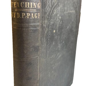 May include: An antique dark gray hardcover book titled Theory and Practice of Teaching by D.P. Page. The spine features gold lettering and a circular emblem at the bottom labeled School Teacher's Library. The cover has an embossed border design.