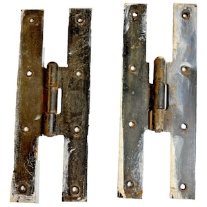 May include: Two antique, weathered metal hinges with a dark, distressed finish. Each hinge has a rectangular shape with multiple screw holes and a central barrel for movement. The hinges show signs of age and wear, with areas of paint loss.
