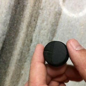 May include: A black round knob with a small groove on the side.