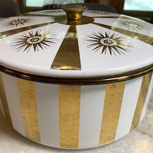 May include: White enamelware pot with a gold lid. The lid has a gold and white starburst design. The pot has vertical gold and white stripes.
