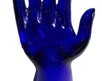 Peut inclure: Un porte-bague en verre bleu cobalt en forme de main. La main est levée, les cinq doigts tendus.