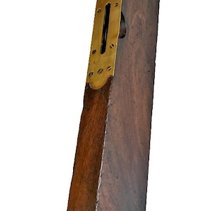Puede incluir: Nivel de madera vintage con placa de latón y orificio circular. El nivel es de madera oscura con un borde más claro, de tono dorado. Una herramienta clásica de carpintería.