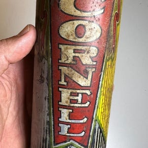 May include: Vintage CORNELL Tube Repair Kit tin. The cylindrical container has a yellow lid and a red and yellow label with the brand name and product information. The tin shows signs of age and wear.