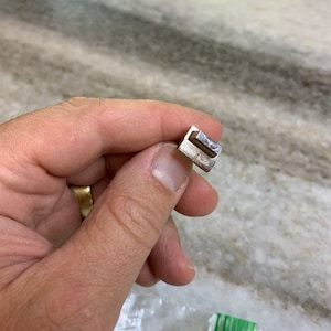 May include: A silver metal key blank with a single cut in the middle.