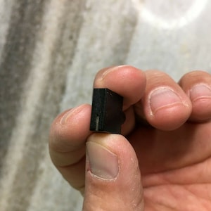 Peut inclure: Un petit objet rectangulaire noir avec une fine ligne blanche qui descend au centre.