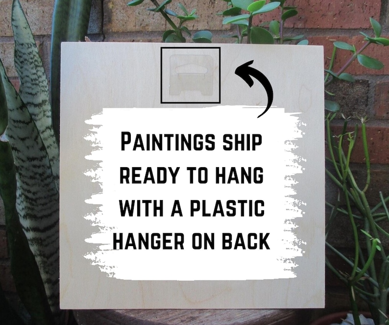以下が含まれることがあります： 「Paintings ship ready to hang with a plastic hanger on back」と黒文字で書かれた白い木製の看板です。