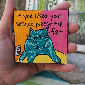 Puede incluir: Pequeña pintura cuadrada con una ilustración de gato turquesa y el texto "if you liked your service. please tip fat" en negro. El fondo está dividido en secciones naranja y rosa.