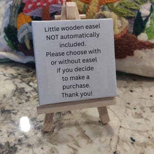 May include: A small, light-colored wooden easel holding a white canvas with text. The text reads: "Little wooden easel NOT automatically included. Please choose with or without easel if you decide to make a purchase. Thank you!"