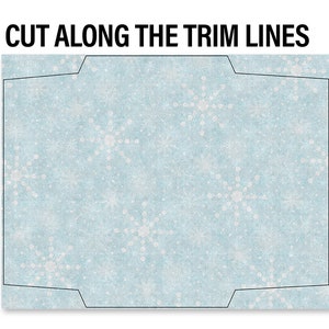 May include: A printable craft template with a light blue background and white snowflake designs. The text "CUT ALONG THE TRIM LINES" is printed at the top of the template.