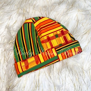 Może przedstawiać: Czapka dla niemowlęcia w zielono-żółto-czerwono-czarne wzory. Czapka jest wykonana z miękkiej, elastycznej tkaniny i idealnie nadaje się do utrzymania ciepła głowy niemowlęcia.