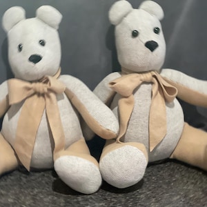 May include: Two handmade gray and beige teddy bears with brown eyes and a beige bow tie.