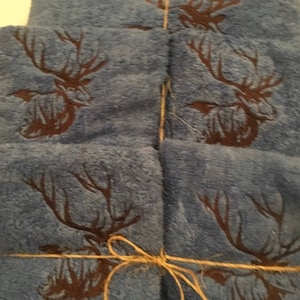 May include: A stack of blue towels with a brown deer design. The towels are tied together with twine.