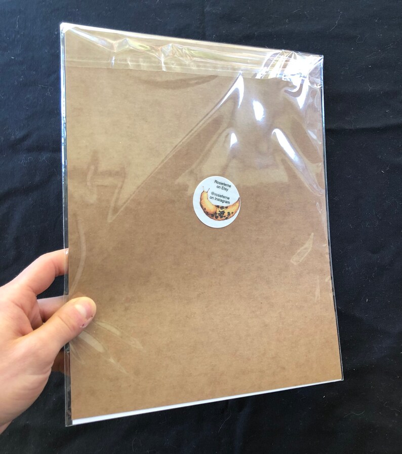 May include: A brown paper print with a round sticker on the bottom right corner. The sticker has a banana with black seeds and the text "Drawesome on Etsy" and "@drawesome on Instagram".