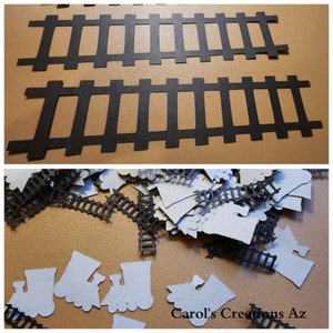 May include: Two black paper train track pieces, one on top of the other, with a pile of black and white paper train track pieces and train engine shapes scattered on a brown surface. The text "Carol's Creations Az" is visible in the bottom right corner of the image.