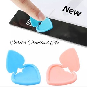 May include: Two heart-shaped phone camera covers, one blue and one pink. The covers are designed to be placed over the camera lens to protect it from scratches and dirt. The covers are made of a soft, flexible material and are easy to apply and remove.
