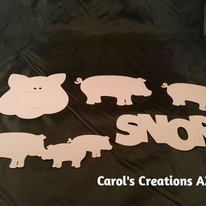 May include: Pink paper pig cutouts with the word "SNORT" in pink paper letters. The pig cutouts are in various sizes and shapes, including a pig head, a pig body, and a pig snout.