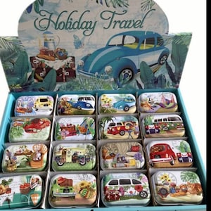 May include: A display of 16 small, rectangular, metal tins with various vintage travel-themed designs. The tins feature images of cars, vans, and other vehicles, along with floral and geometric patterns. The display is labeled "Holiday Travel" and features a blue Volkswagen Beetle.