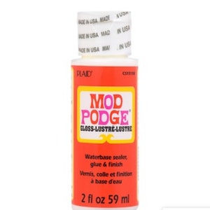 May include: A bottle of Mod Podge Gloss-Lustre waterbase sealer, glue, and finish. The bottle is white with a red label and yellow accents. The label includes the text "MOD PODGE" and "GLOSS-LUSTRE-LUSTRE". The bottle contains 2 fl oz or 59 ml.