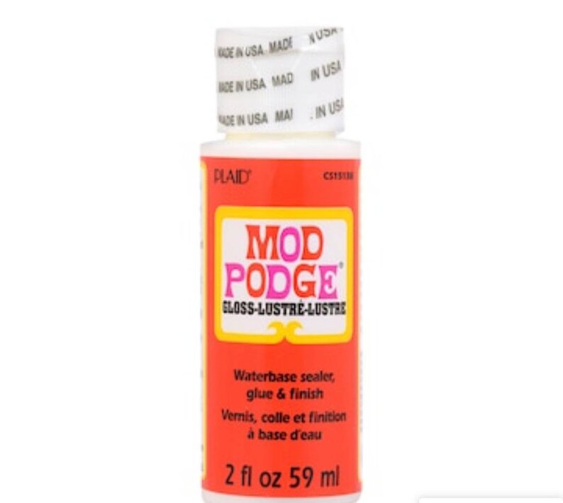 May include: A bottle of Mod Podge Gloss-Lustre waterbase sealer, glue, and finish. The bottle is white with a red label and yellow accents. The label includes the text "MOD PODGE" and "GLOSS-LUSTRE-LUSTRE". The bottle contains 2 fl oz or 59 ml.