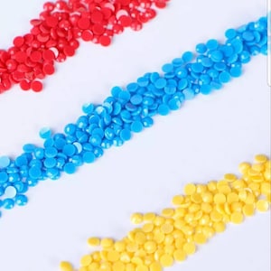 May include: Three rows of colorful round beads, red, blue, and yellow, arranged in a diagonal pattern on a white background.