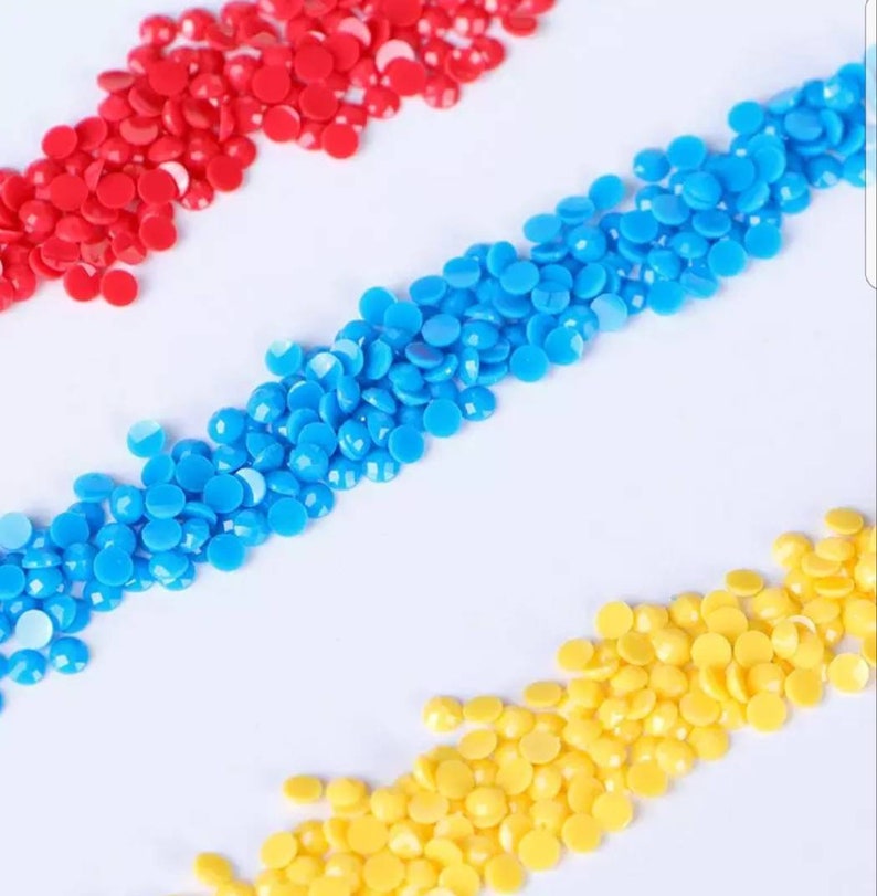 May include: Three rows of colorful round beads, red, blue, and yellow, arranged in a diagonal pattern on a white background.
