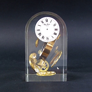 May include: A clear acrylic block containing a clock face and clockwork gears. The clock face reads "Big Ben London".