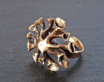 May include: A bronze ring with a unique design resembling a stylized coral or branching tree. The ring is open and adjustable.