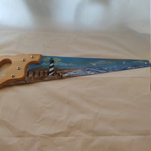 Hand painted 18 inch hand saw. Painted in Cape Hatteras lighthouse and ocean scene. Made in the USA. New
