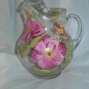Hand painted round pitcher in fun soft pink poppies and yellow and orange accents. 66 ounces.
