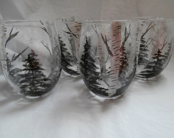 May include: Four clear glass tumblers with hand-painted winter scenes. Each glass features a black and white illustration of a snowy forest with birch trees and pine trees.