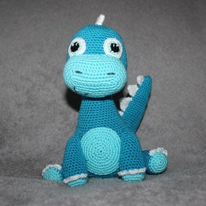 May include: A crocheted blue dinosaur toy with white accents and large black eyes.