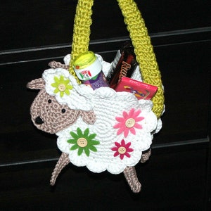 May include: A white crocheted lamb shaped bag with a yellow handle. The bag is filled with candy and other treats.