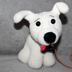May include: White crocheted dog toy with black eyes, nose, and collar. The dog has a pink tongue sticking out and is holding a brown leash.