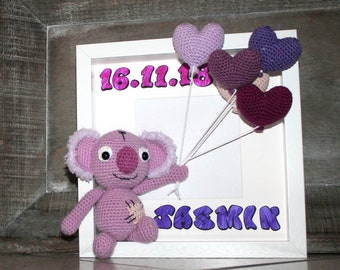 May include: A white picture frame with a pink crocheted koala holding purple heart balloons. The frame has the date "16.11.18" and the name "JASMINE" written in purple.