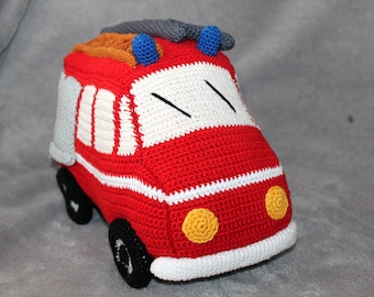 May include: A red crocheted fire truck toy with white stripes, yellow headlights, and a gray ladder on top. The toy has black wheels and blue and orange details.