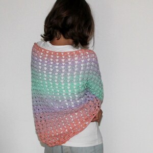 May include: A crocheted shawl with a gradient of pink, orange, green, and purple.