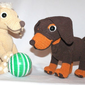 May include: Two crocheted stuffed dogs, one beige and one brown with orange accents, playing with a green and white striped ball.