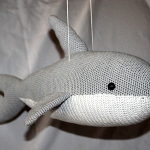 May include: A gray and white crocheted shark hanging toy with black eyes.